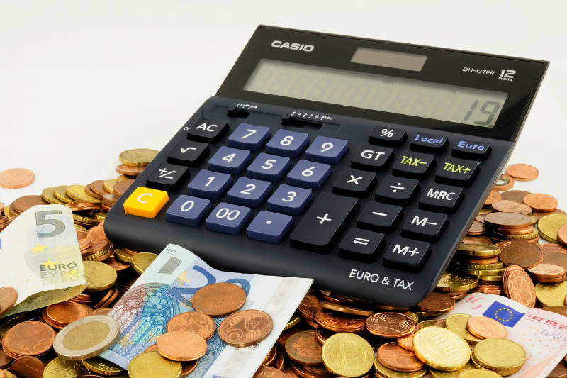 Foto van een rekenmachine met daaromheen eurobiljetten en muntjes.